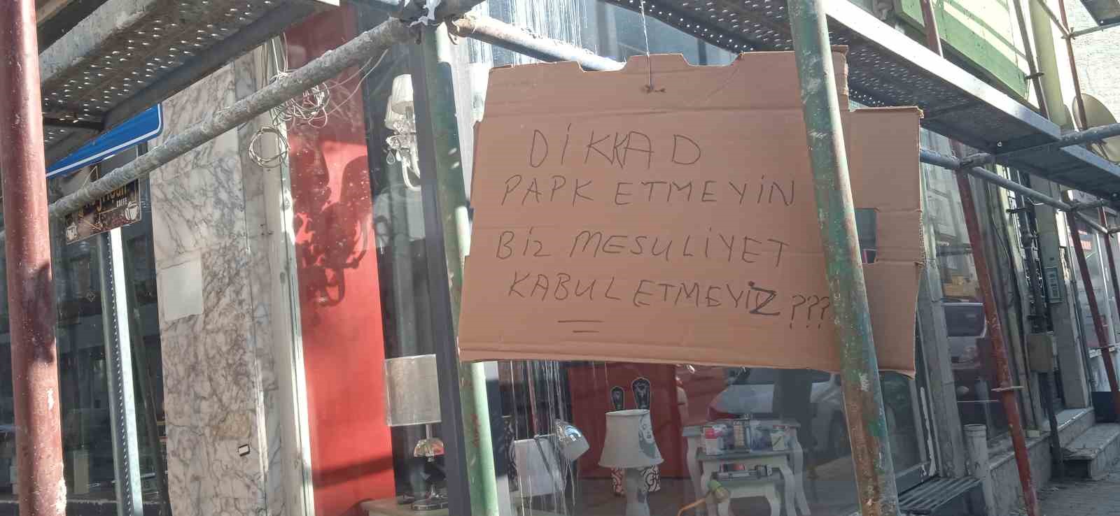 İNŞAAT ÇALIŞMALARI İÇİN BİNAYI ÇEVRELEYEN DEMİRLERE İPLE BAĞLANAN KARTONDAKİ YAZI