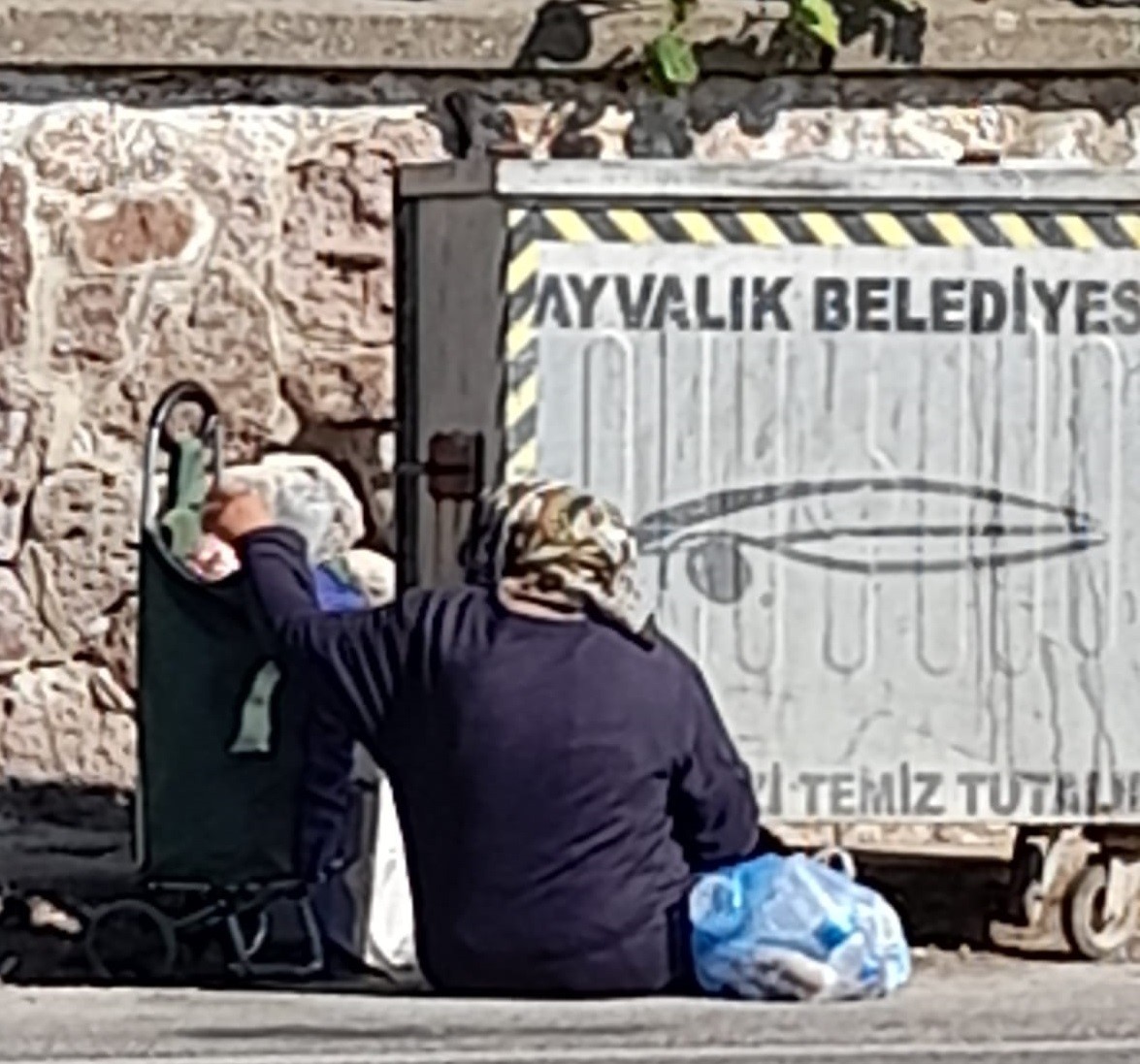 BALIKESİR’İN AYVALIK İLÇESİNDE, ÇÖP KONTEYNERLERİNDEN TOPLADIKLARI EKMEKLERİ YİYOR GİBİ GÖRÜNÜP,